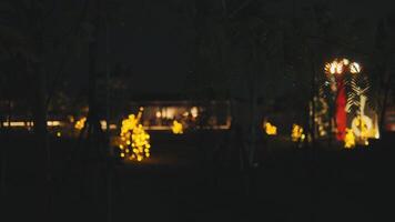 borroso noche escena con indistinto iluminado cifras y árboles, creando un misterioso y temperamental atmósfera. video