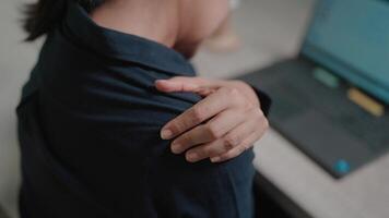 Close-up of tired woman having shoulder pain while working on laptop while sitting at table in modern office. video