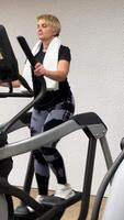 Mature woman uses a step machine in the gym. video