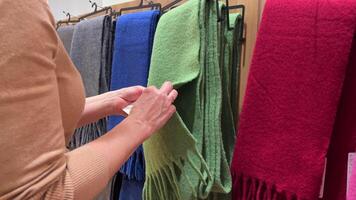 A woman chooses a warm scarf in a shopping center, close-up. video