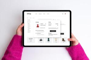 E-commerce cart page on a tablet with price, delivery options, and checkout button. Woman buys a red dress, creating a seamless and stylish online shopping experience photo