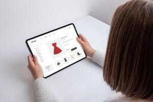 mujer sostiene tableta con un comercio electrónico Página web, buscando para un rojo vestido. moderno compras a su puntas de los dedos, mezcla tecnología y Moda en un contemporáneo ajuste foto