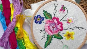 The process of hand embroidering a napkin with colored threads on white fabric. video