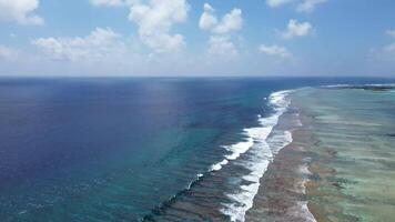 zangão Visão do paraíso ilhas do a Maldivas com coral recifes debaixo a ondas do a indiano oceano. video