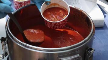 Tomato soup with pasta is a Polish dish. Zupa pomidorowa. Hot soup made from grated tomatoes. People and tourists walk, eat and buy food at the street food festival. Ukraine, Kyiv - August 17, 2023. video