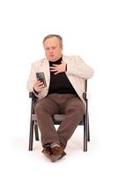 man in a chair experiences emotions while watching something on his phone on a white background photo