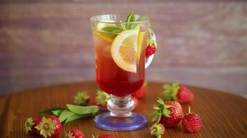 refreshing cool strawberry lemonade with lemon, ice and mint in a glass on a wooden table video