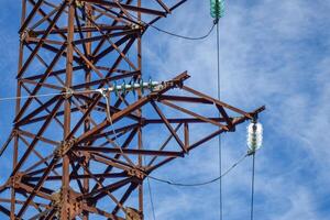 Supports high-voltage power lines against the blue sky with clouds. Electrical industry photo