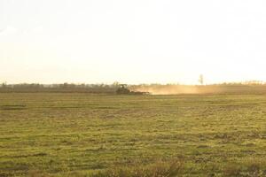 Tractor at sunset plow plow a field. Tilling the soil in the fall after harvest. The end of the season photo