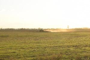 tractor a puesta de sol arado arado un campo. labranza el suelo en el otoño después cosecha. el final de el temporada foto