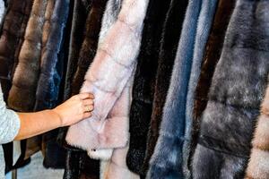 el niña toques el piel en el piel abrigo. elegir un piel Saco en el Tienda foto