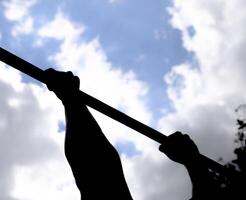 Silhouette of hands on a horizontal bar. Hands on the bar close-up. The man pulls himself up on the bar. Playing sports in the fresh air. Horizontal bar. photo