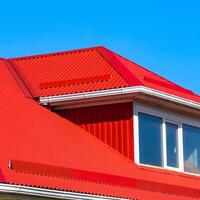 House with plastic windows and a red roof of corrugated sheet photo