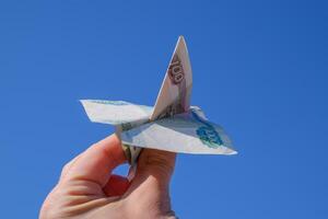 Denominations of Russian money, folded in the airplane against the blue sky in hand photo