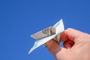 Denominations of Russian money, folded in the airplane against the blue sky in hand photo