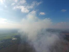 The smoke over the village. Clubs of smoke over the village houses and fields. Aerophotographing areas photo