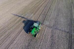 Tractor with hinged system of spraying pesticides. Fertilizing with a tractor, in the form of an aerosol, on the field of winter wheat. photo