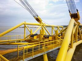 Laying of pipes with pipe-laying barge crane near the shore. Descent of the pipeline to a bottom exhausting with the pipelaying barge. Installation of the underwater gas pipeline photo