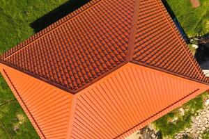 House with an orange roof made of metal, top view. Metallic profile painted corrugated on the roof. photo