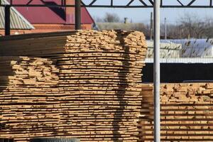 Warehouse of building materials, wood planks stacked under a canopy photo