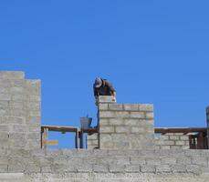 The builder builds the wall of the house from the cinder block. Worker at the construction site. photo