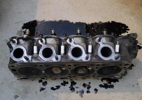 The head of the block of cylinders. The head of the block of cylinders removed from the engine for repair. Parts in engine oil. Car engine repair in the service photo