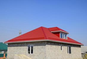 Red corrugated roof. House of cinder block. House with plastic windows and roof of corrugated sheet photo