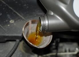 Oil change in the engine of the car. Filling the oil through the funnel. Car maintenance station. photo