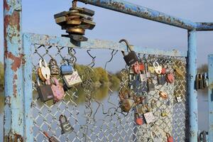 Love locks hung by newlyweds and lovers on the fence near the river. A symbol of strong relationships and eternal love photo