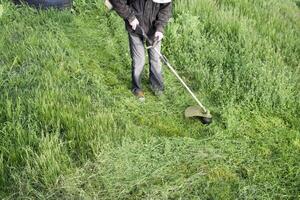 Application trimmers. Mowing green grass using a fishing line trimmer photo