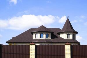 Decorative metal on the roof of a brick house. Fence made of corrugated metal. photo