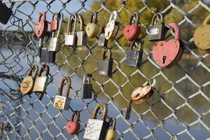 Love locks hung by newlyweds and lovers on the fence near the river. A symbol of strong relationships and eternal love photo