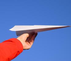 White paper airplane in hand against the sky. A symbol of freedom on the Internet photo