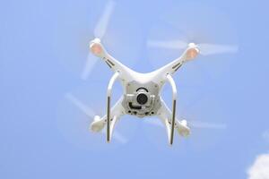 Drone DJI Phantom 4 in flight. Quadrocopter against the blue sky with white clouds. The flight of the copter in the sky. photo