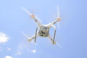 Drone DJI Phantom 4 in flight. Quadrocopter against the blue sky with white clouds. The flight of the copter in the sky. photo