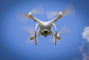 Drone DJI Phantom 4 in flight. Quadrocopter against the blue sky photo