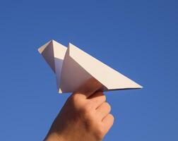 White paper airplane in hand against the sky. A symbol of freedom on the Internet photo