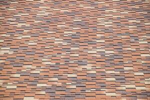 Roof from multi-colored bituminous shingles. Patterned bitumen shingles. photo