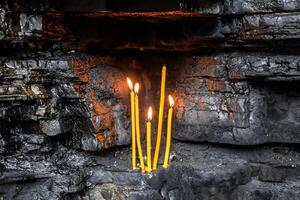 Wax church candles in rock niches. Holy place photo