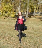 A woman is posing in front of a camera in an autumn park. autumn photo shoot. Autumn in the park