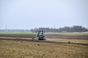 Lush and loosen the soil on the field before sowing. The tractor plows a field with a plow photo