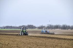 lozano y aflojar el suelo en el campo antes de siembra. el tractor arados un campo con un arado foto