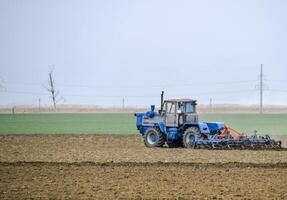 lozano y aflojar el suelo en el campo antes de siembra. el tractor arados un campo con un arado foto