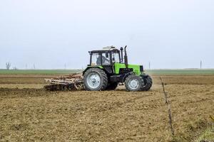 Lush and loosen the soil on the field before sowing. The tractor plows a field with a plow photo