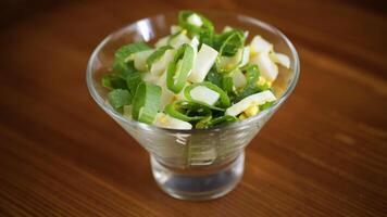 fresh spring salad with boiled squid, boiled eggs and green onions on a wooden table video