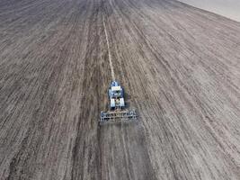 The tractor plows the field. Under sowing, the soil is loosened on the field. photo