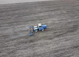 The tractor plows the field. Under sowing, the soil is loosened on the field. photo