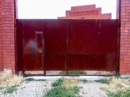 Steel rusty gates and a red brick fence. photo