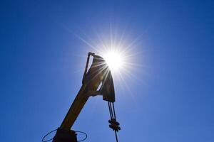 Head counterweight oil pump jack backlit. Oil equipment against photo