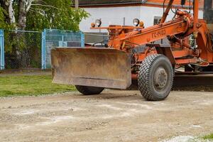 Grader on a dirt gravel road. Street repair by adding rubble. photo